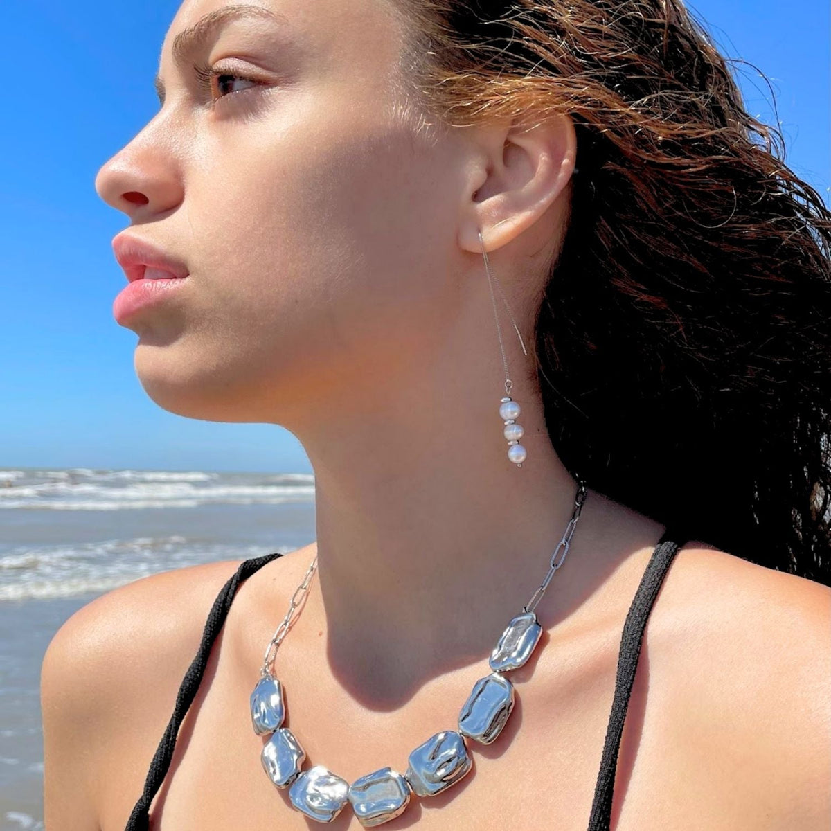 Woman wearing a necklace and earrings with a beach background