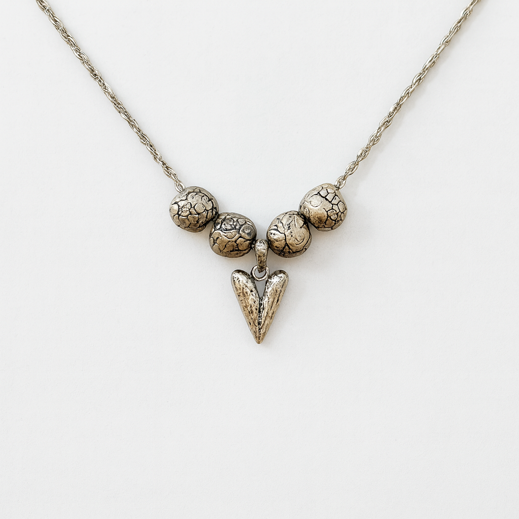 Silver necklace with textured beads and a triangular pendant on a white background