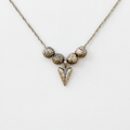 Silver necklace with textured beads and a triangular pendant on a white background