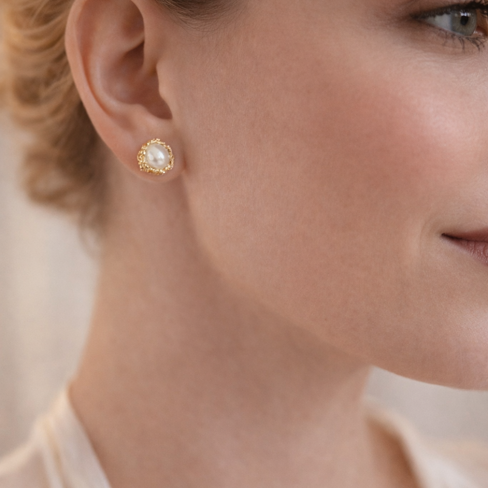 Close-up of a woman wearing gold earrings with a blurred background
