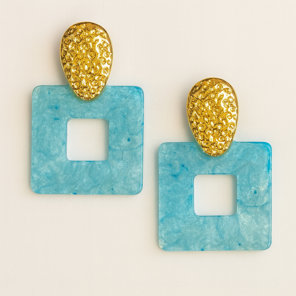 Pair of earrings with gold and blue designs on a light beige background