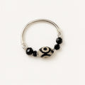 Silver ring with black and white beads on a white background