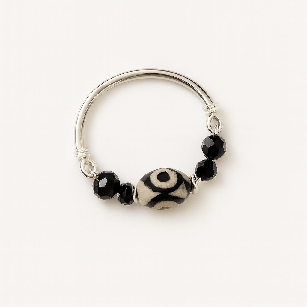 Silver ring with black and white beads on a white background