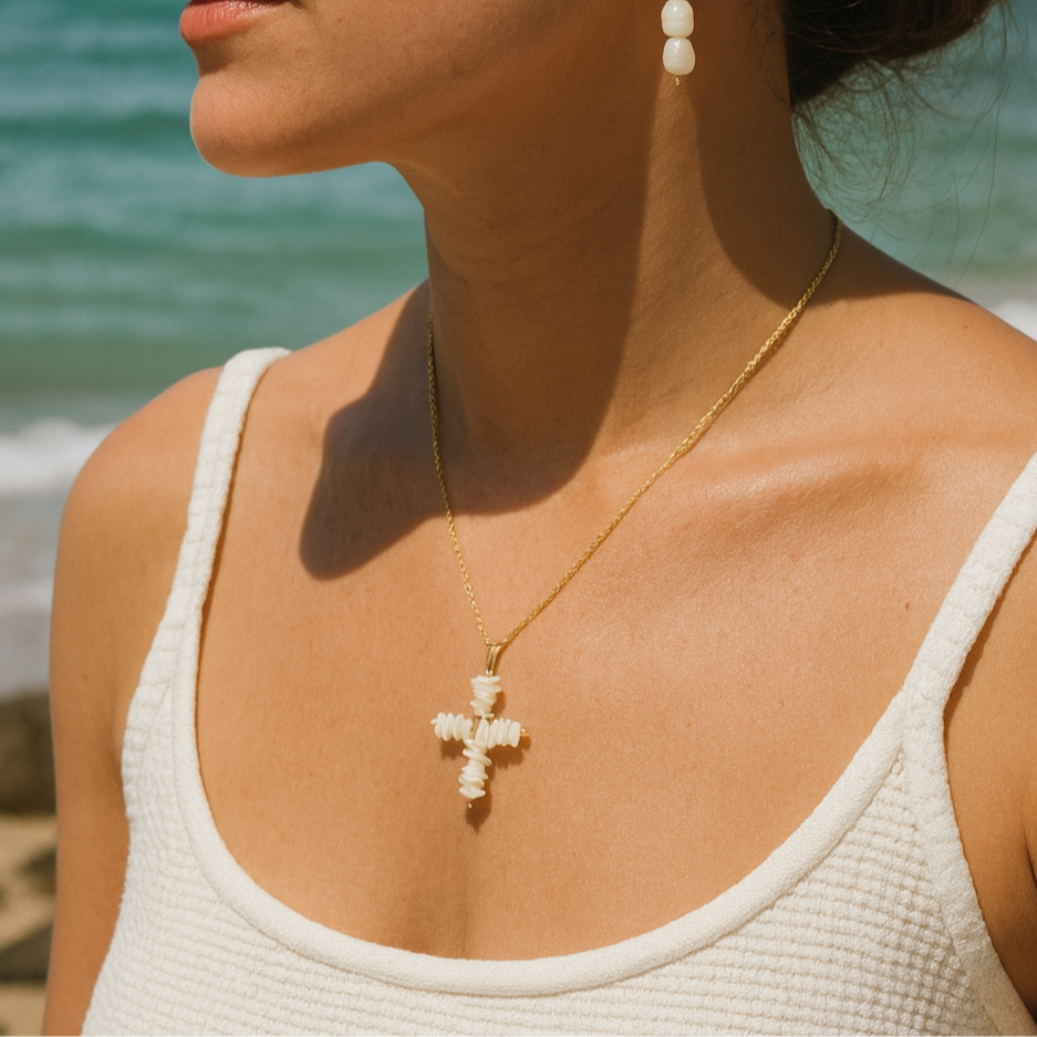 Woman wearing earrings and a necklace with a beach in the background