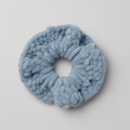 Blue fluffy scrunchie on a light gray background