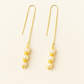 Pair of pearl earrings with gold accents on a light beige background