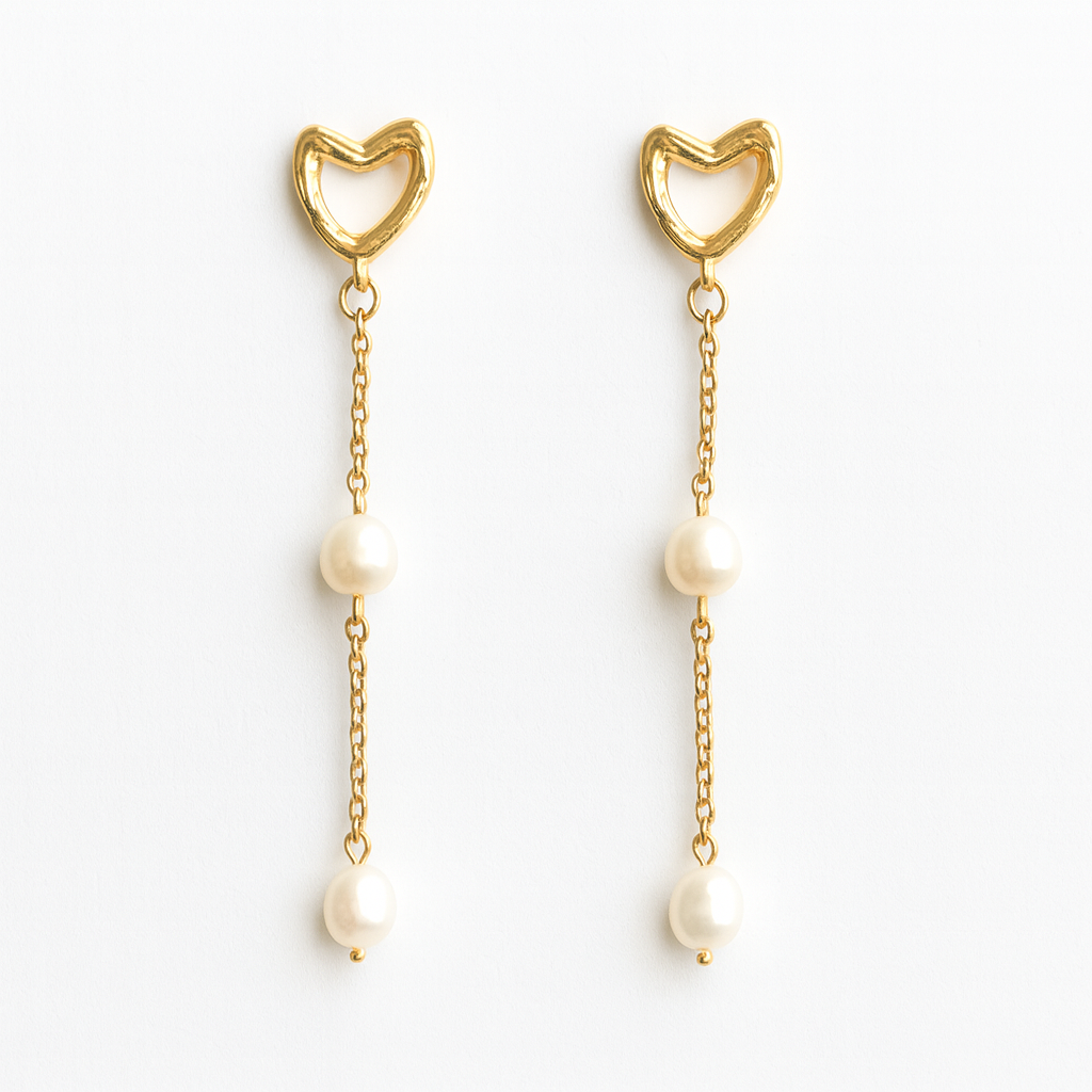 Gold heart-shaped earrings with pearl drops on a white background