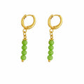 Gold hoop earrings with green bead drops on a white background