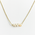 Gold necklace with pearls on a light gray background