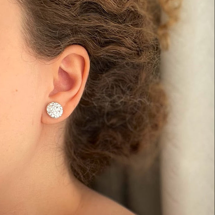 Close-up of a person wearing a diamond earring with a neutral background