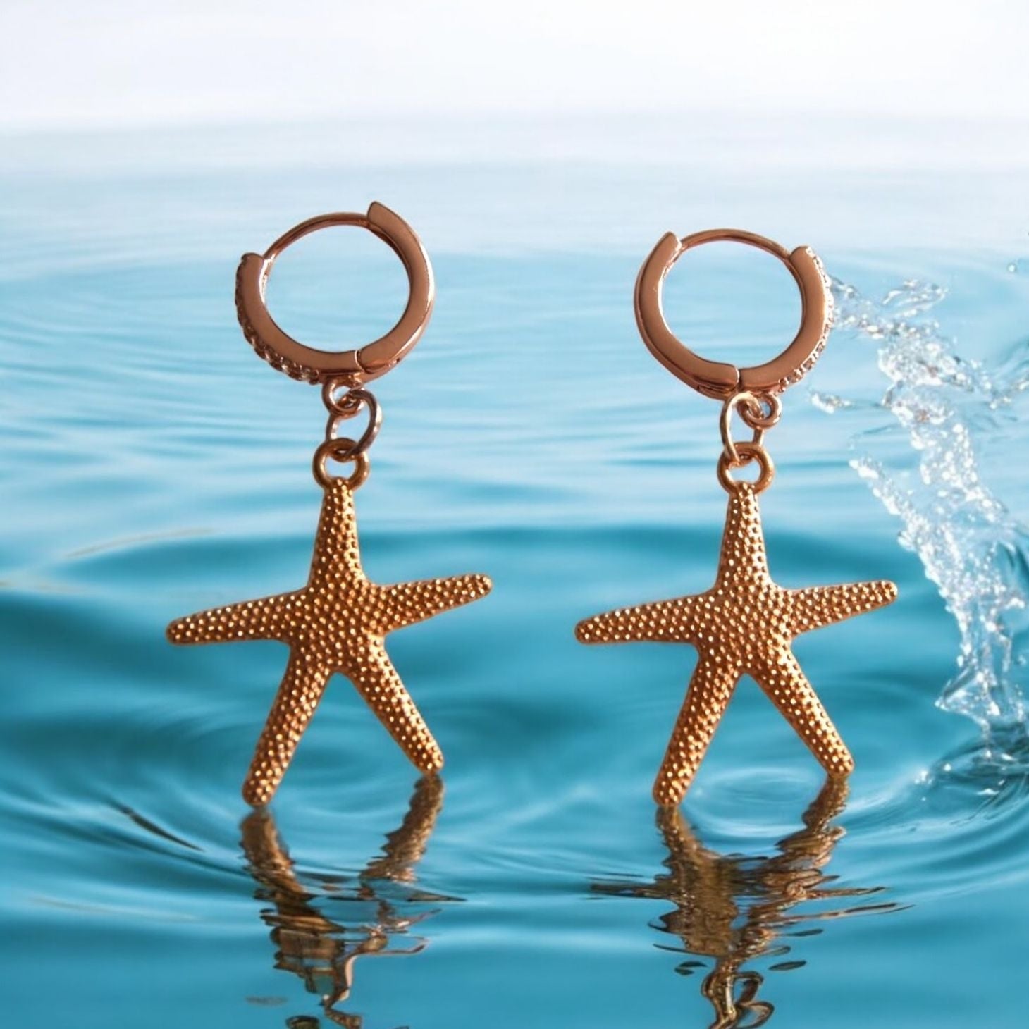 Gold starfish earrings on a water background