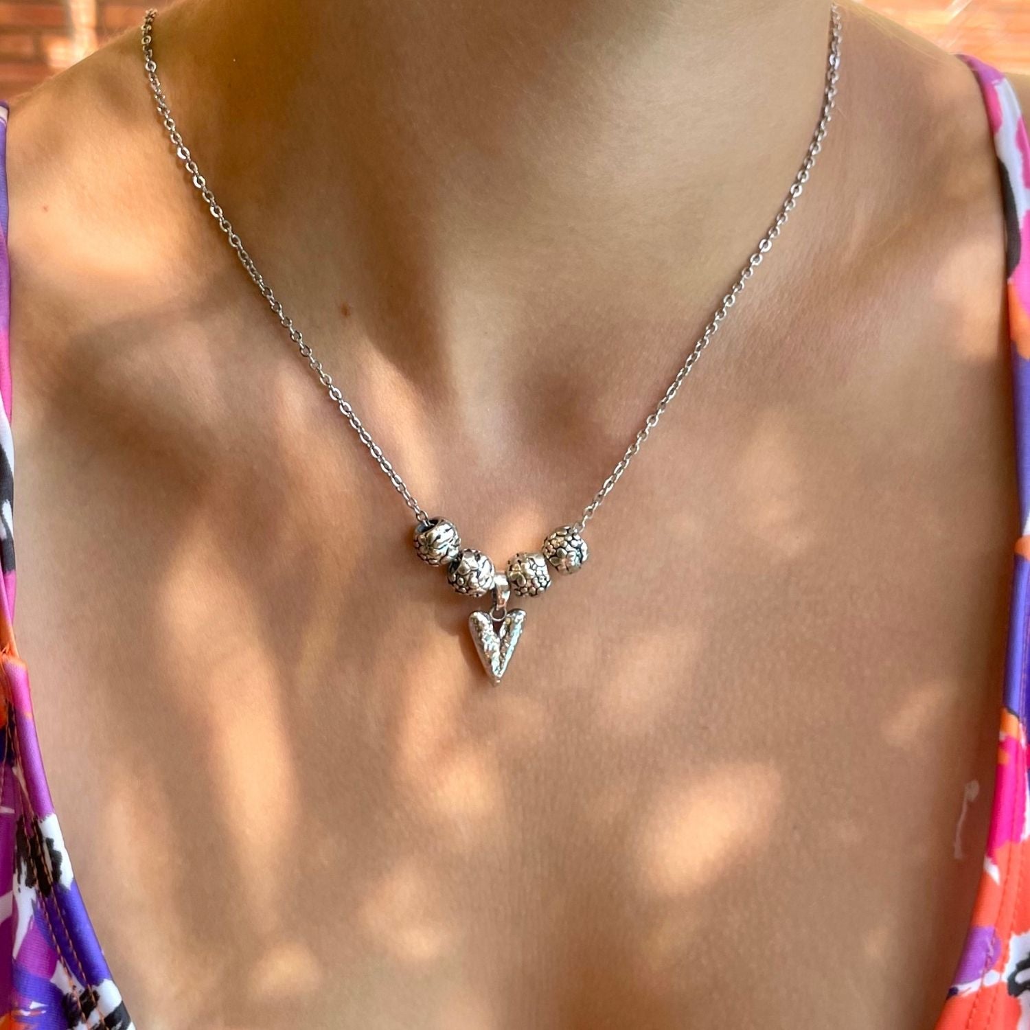 Necklace with a pendant worn by a person, with a colorful garment partially visible.