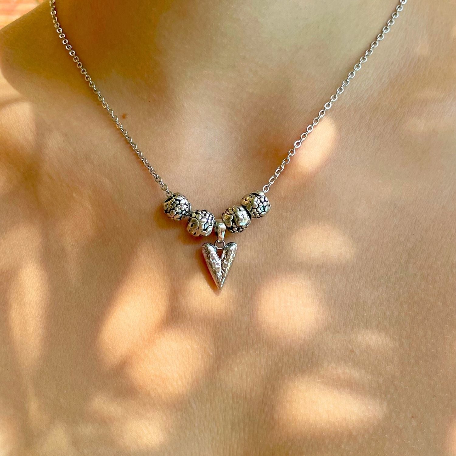 Silver necklace with a heart pendant on a blurred background