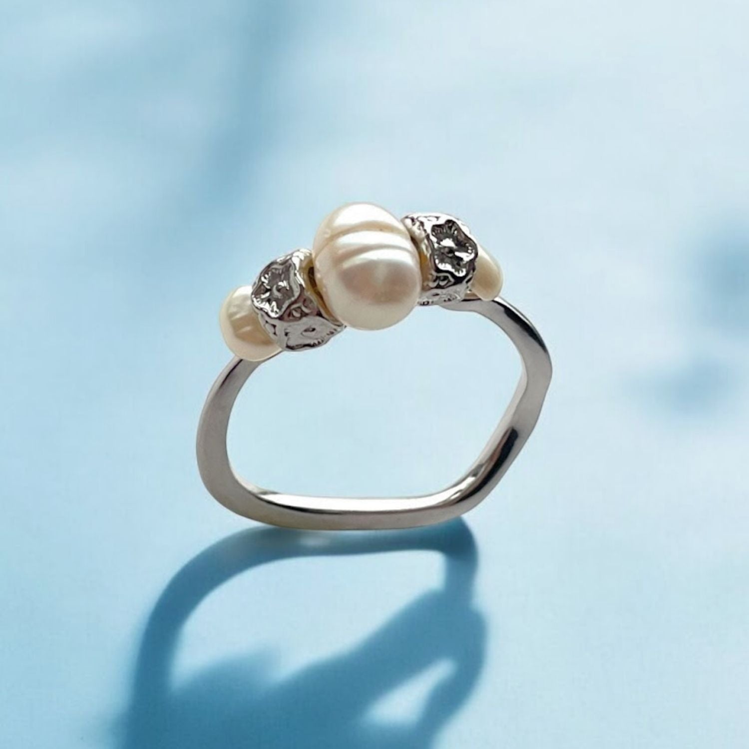 Silver ring with pearls on a light blue background