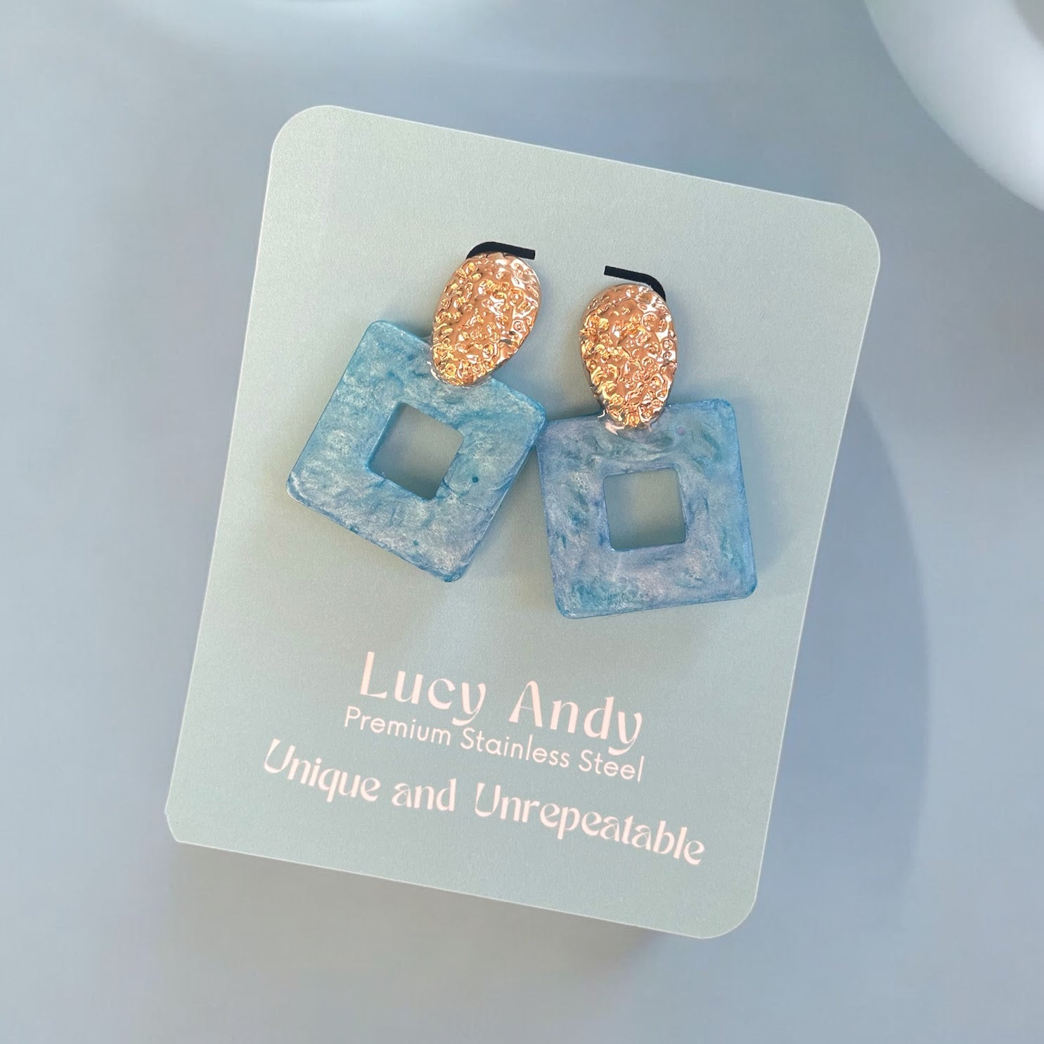 Pair of earrings on a Lucy Andy branded card with a light background