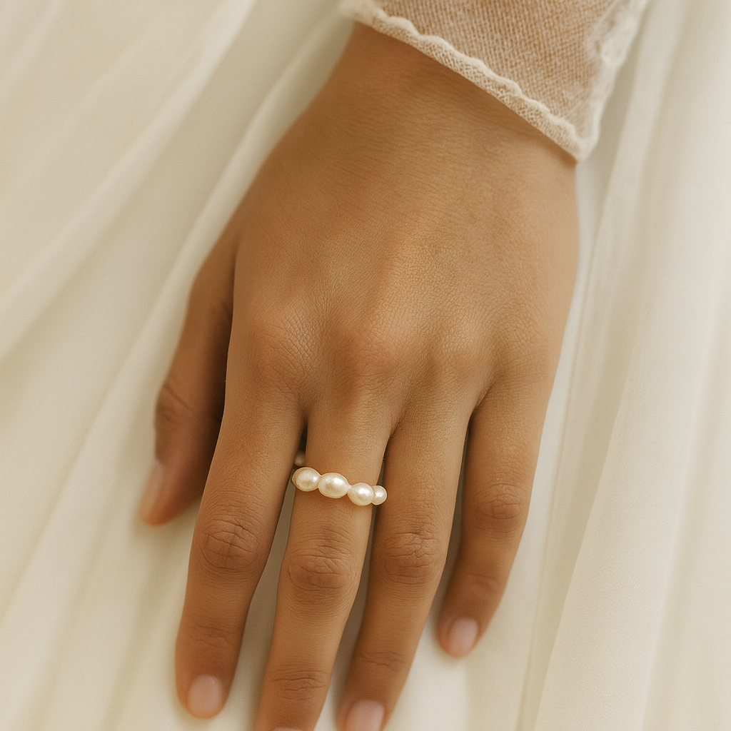 Hand wearing a pearl ring on a soft, light background