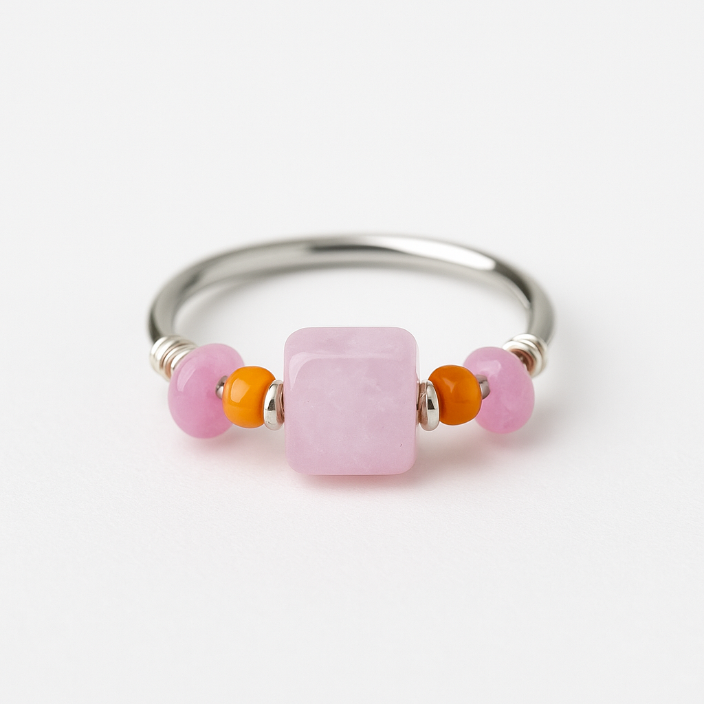 Silver ring with pink and orange beads on a white background
