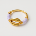 Gold ring with a shell design and purple beads on a light gray background