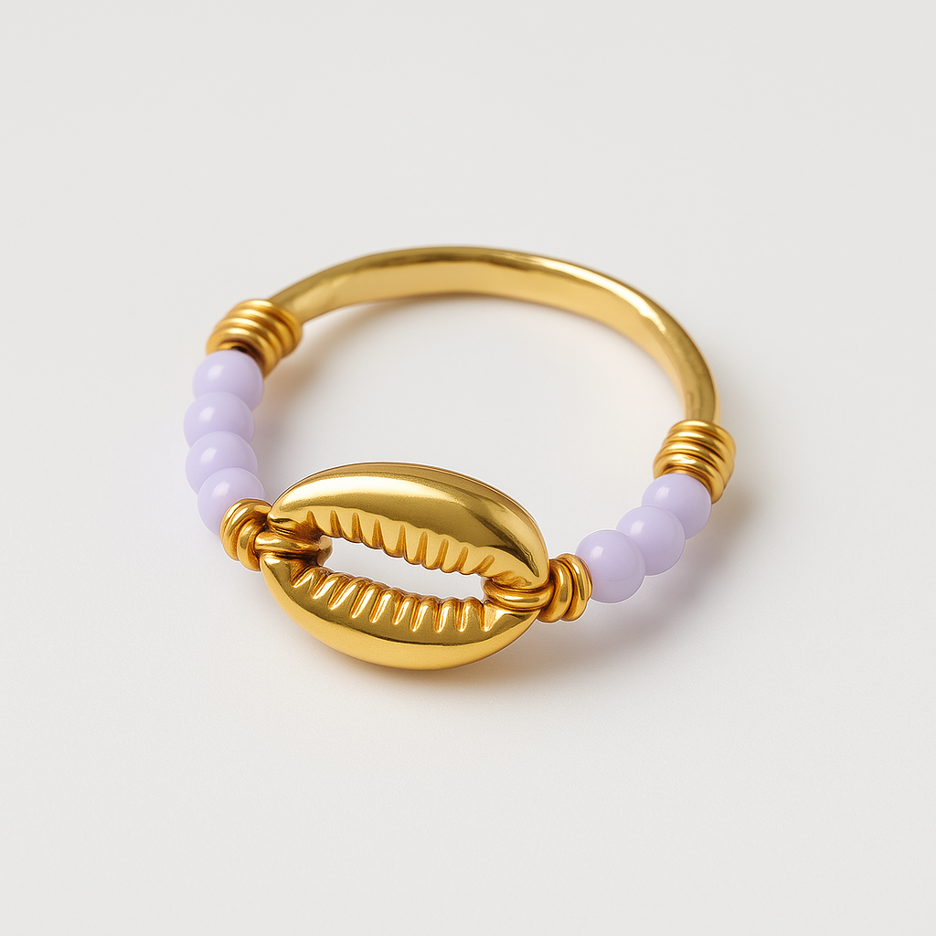 Gold ring with a shell design and purple beads on a light gray background