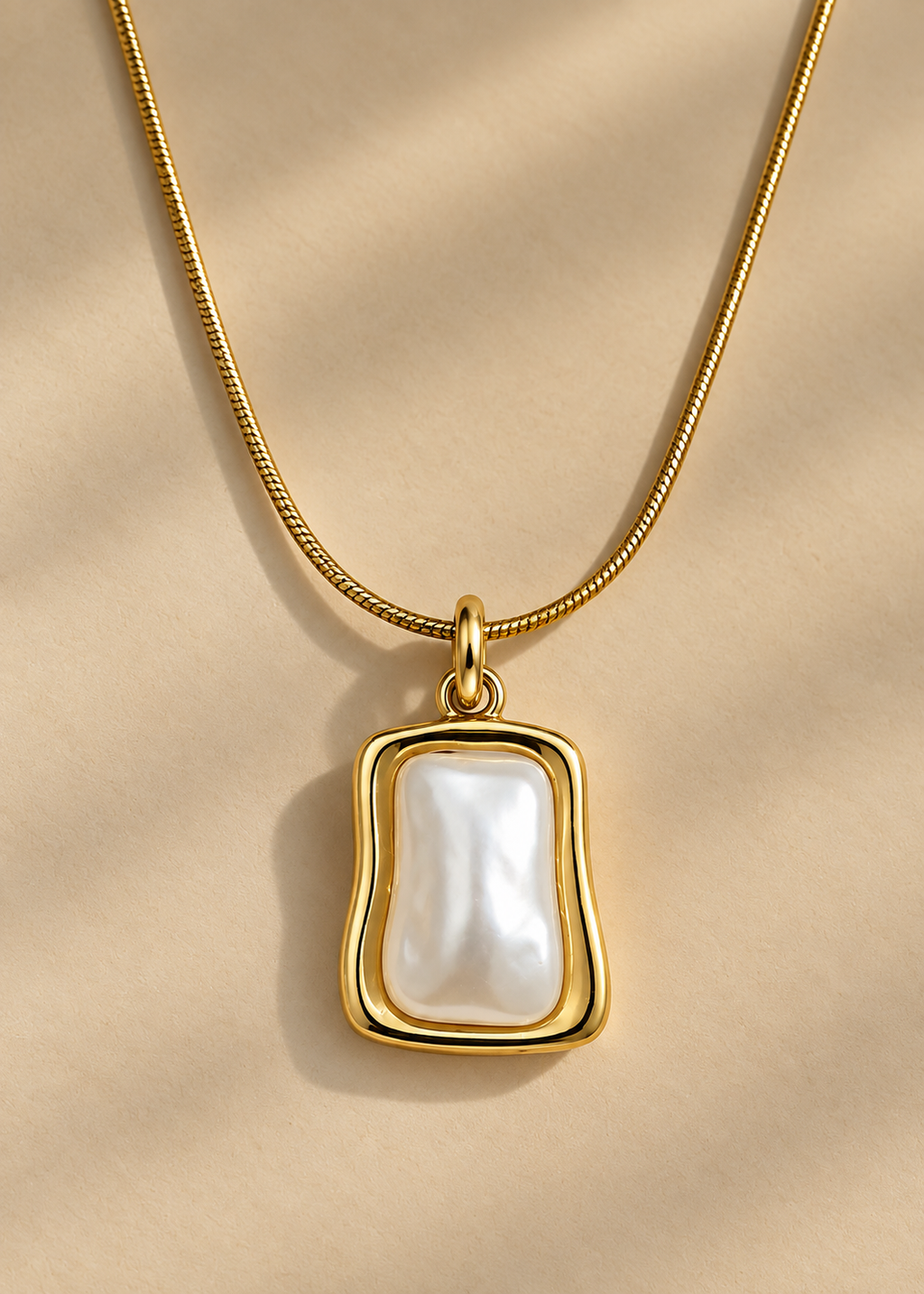 A delicate gold chain necklace with a teardrop-shaped white pearl pendant, softly lit background.