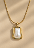 A delicate gold chain necklace with a teardrop-shaped white pearl pendant, softly lit background.
