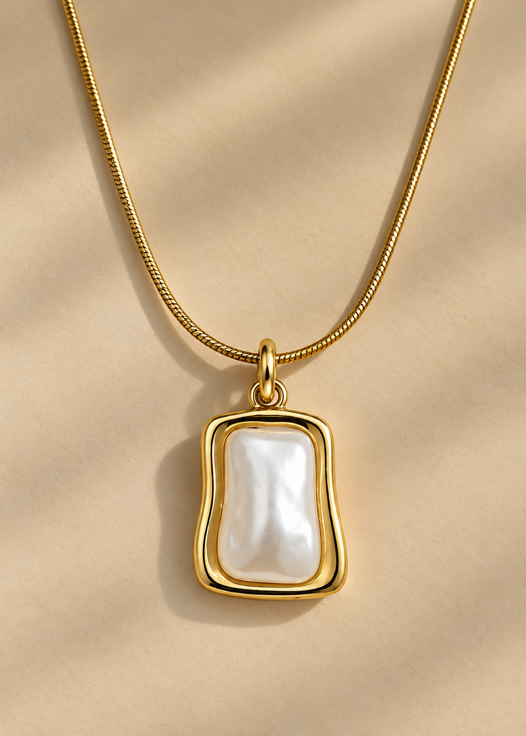 A delicate gold chain necklace with a teardrop-shaped white pearl pendant, softly lit background.