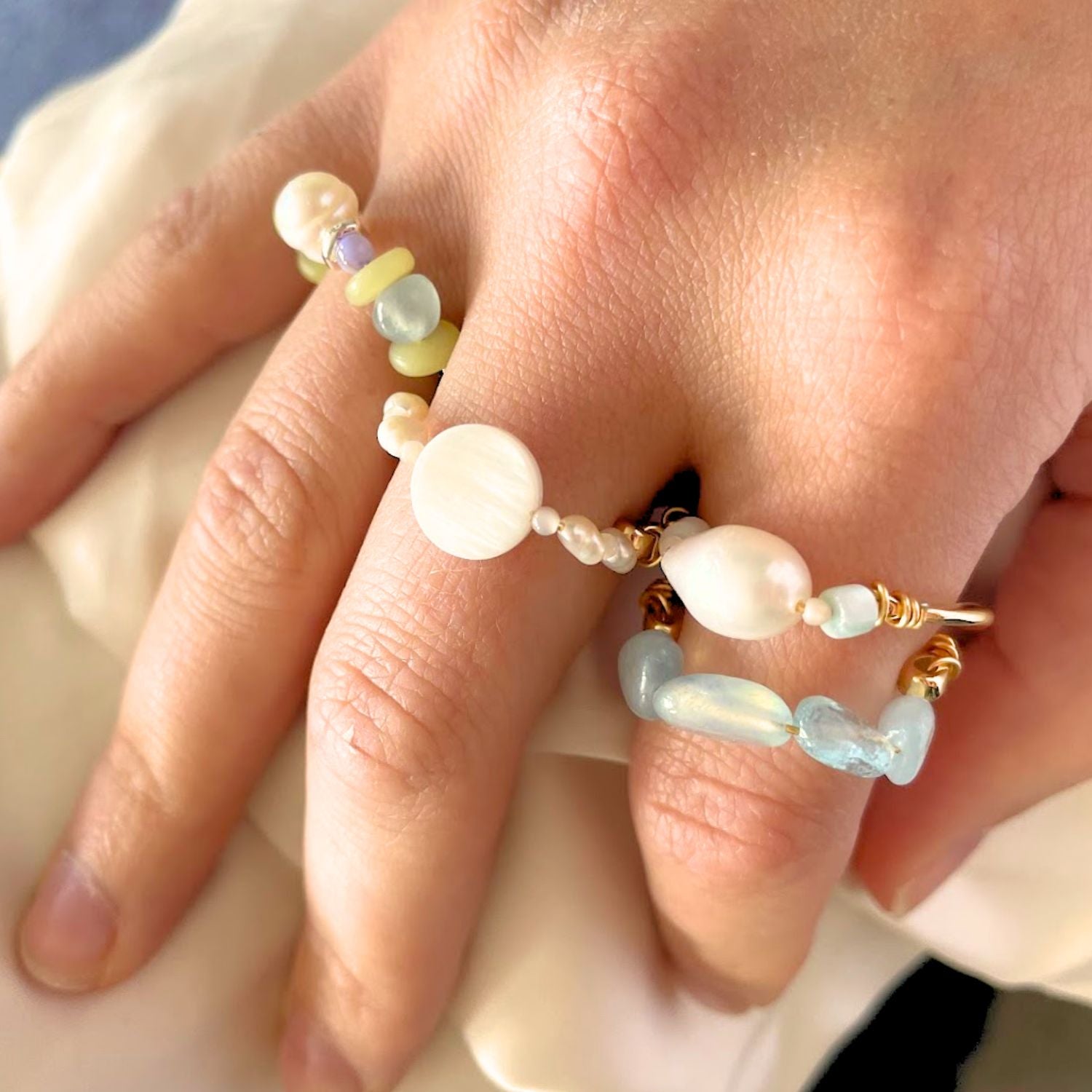 Close-up of a hand wearing a beaded ring with pearls and gold accents.