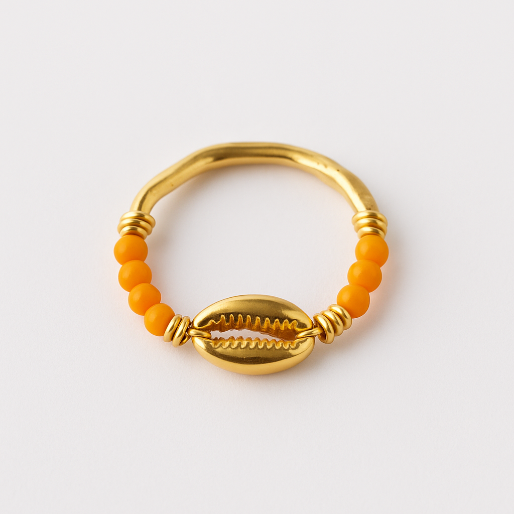 Gold ring with orange beads and a shell design on a white background