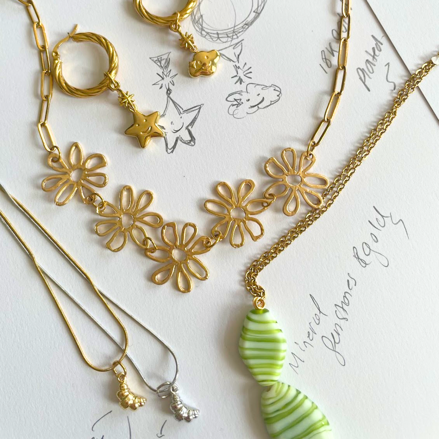 Gold and silver jewelry including necklaces and earrings on a white surface with decorative text.