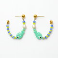 Pair of fish-shaped beaded earrings on a white background