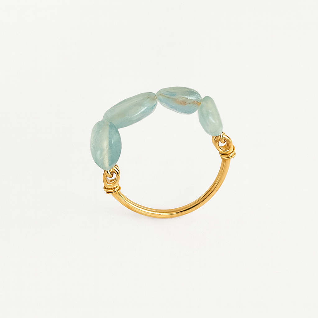 Gold ring with light blue gemstones on a white background