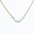 Necklace with light blue beads on a gold chain against a white background