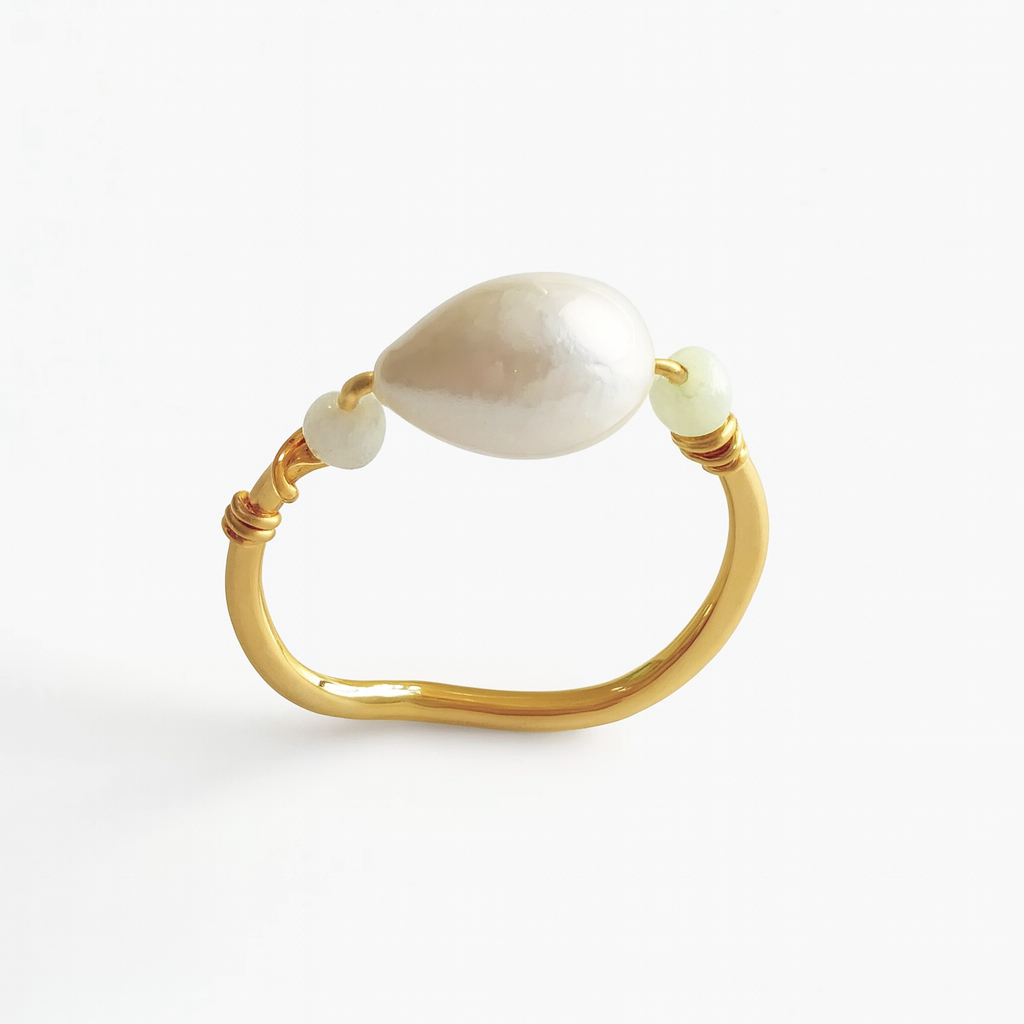 Gold ring with a large pearl and smaller beads on a white background