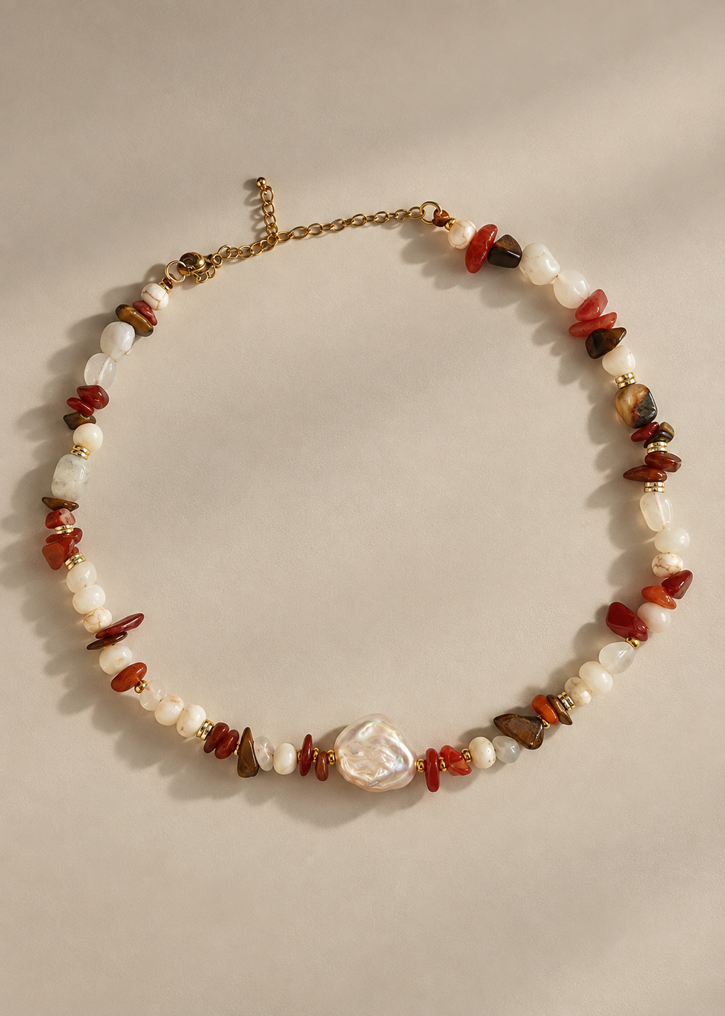 A beaded necklace with white baroque pearls, polished red and brown stone chips, and a central irregular white pearl pendant, displayed on a neutral beige background.