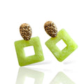 Pair of earrings with square green stones and gold tops on a white background