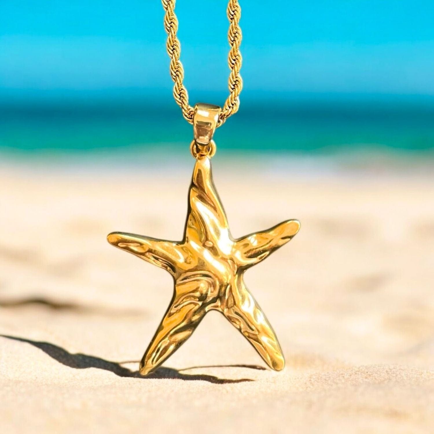 Gold starfish pendant on a rope chain with a beach background
