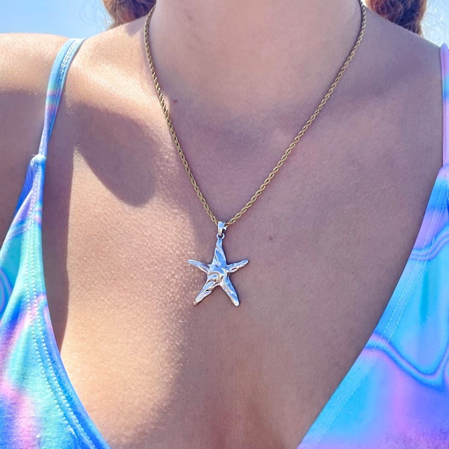 Starfish pendant necklace on a person wearing a colorful swimsuit.