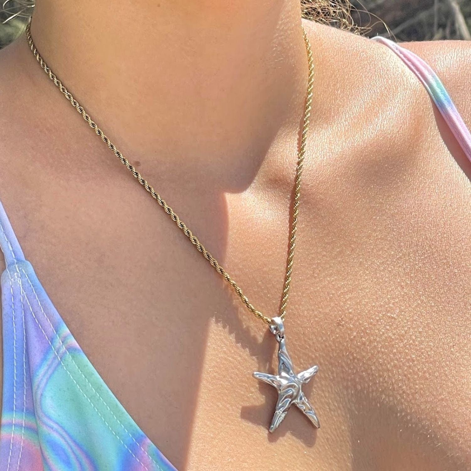 Starfish pendant necklace on a person wearing a colorful bikini.
